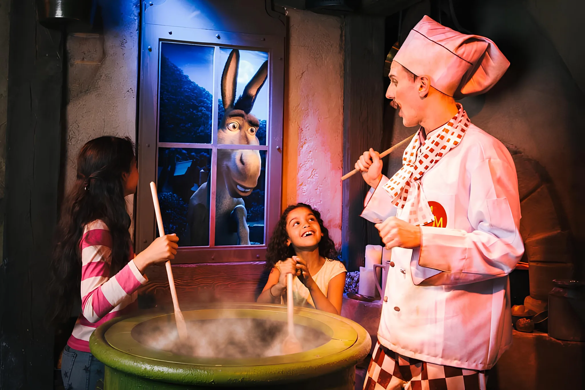 A photo of two female children and a chef enjoying Shrek's Adventure London.